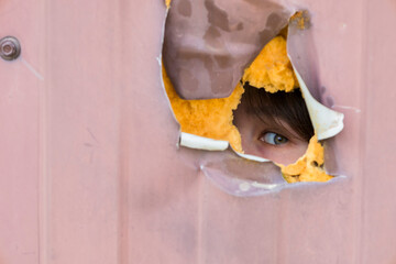 A Curious Gaze Looking Through a Hole in the Wall, Inspiring Wonder