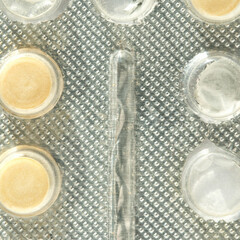 Close-up of medication blister pack with empty and filled pill slots in transparent packaging material.
