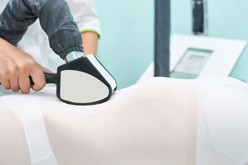 Fototapeta premium Female receiving non-invasive body contouring treatment in medical spa setting.