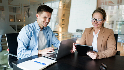 Two colleagues collaborating in a modern office setting, sharing ideas and working on technology