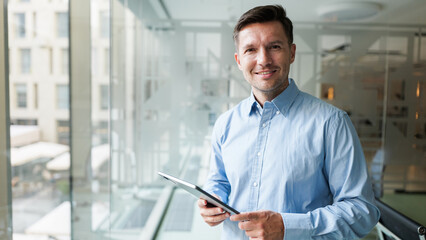 Business professional stands in modern office while using a tablet