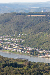 Scenic view of the Rhine River near Bad Salzig in Germany with a cargo ship navigating the waterway and lush hills in the background