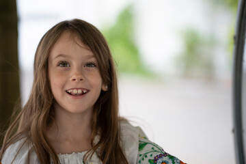Smiling Ukrainian girl in an embroidered blouse with loose hair showing her teeth, concept of childhood and dental health