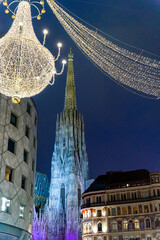 Fototapeta premium Gothic cathedral illuminated at night with Christmas street decorations in Vienna