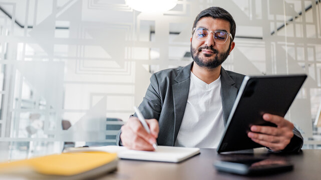 Man working on a tablet and taking notes in a modern office space