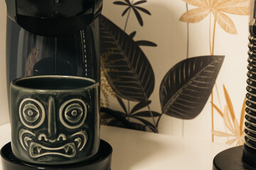 Demon-faced teacup in a coffee pot