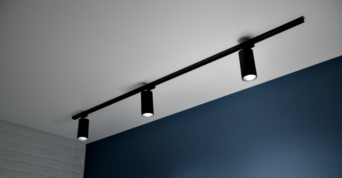 Modern ceiling track lighting with three adjustable spotlights illuminating a stylish interior, featuring a sleek design and contrasting wall colors for contemporary ambiance