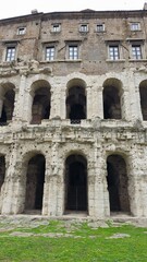 Rome, Italy - 11 January 2025. This close-up captures the central arches and aged textures of the Theatre of Marcellus, with barred gates below and brick upper stories with windows above.