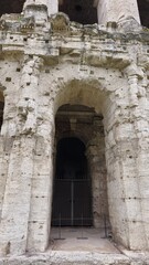 Fototapeta premium Rome, Italy - 11 January 2025. This close-up shows a gated archway at the base of the Theatre of Marcellus, surrounded by weathered limestone and architectural details above.