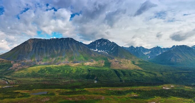 Amazing mountains with little snow on the slopes. Sky covered with clouds above. Spectacular nature of Alaska, USA. Aerial view.