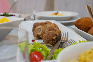 Roasted meat rolls served on a white plate with lettuce and tomato garnish on a festive dining table.