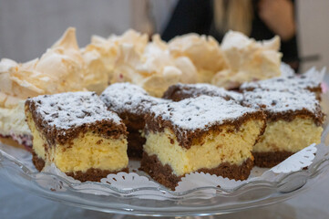 Homemade layered chocolate and vanilla cream cake slices with powdered sugar on a glass plate.