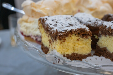 Homemade layered chocolate and vanilla cream cake slices with powdered sugar on a glass plate.