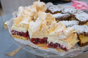 Assorted layered cakes with whipped cream, meringue, and berry filling served on a glass plate.