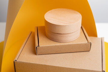 Eco friendly cardboard boxes and round kraft packaging on yellow and gray background. Minimal composition for branding, product presentation, or cosmetic packaging mockup.
