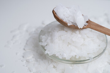Close-up of magnesium salt flakes. Spa body care and magnesium therapy. White salt, cotton towels, eco-friendly products for home relaxation spa.
