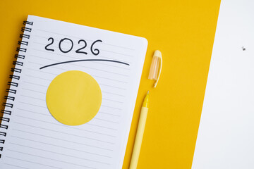 Happy New Year 2026 and a notepad on a colored background. Layout for writing annual business...