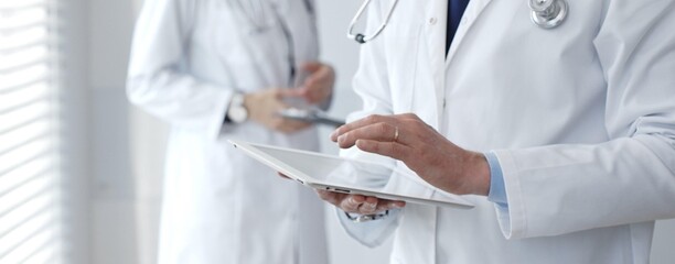Doctors working together on medical records while a healthcare professional uses a digital tablet...