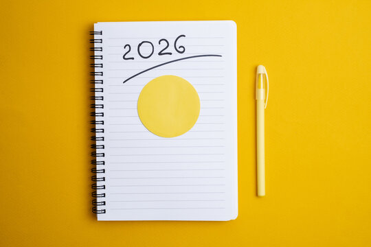 Happy New Year 2026 and a notepad on a colored background. Layout for writing annual business plans, schedules, as well as New Year's resolutions and goals.  

