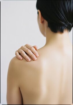 	Woman touching bare shoulder symbolizing body awareness softness and calm in mindful wellness routine