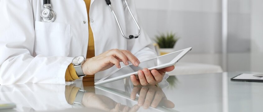 Female doctor using digital tablet, providing modern healthcare and medical technology consultation. Medicine, healthcare and science concept - Powered by Adobe
