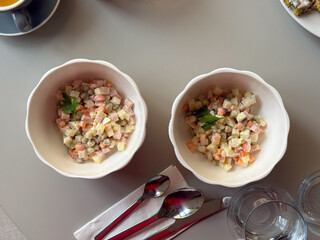 Two white bowls of Olivier salad on a cafe table. Shared dining, culinary tradition and cultural nostalgia expressed through classic homemade cuisine.