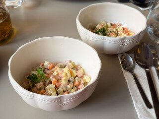 Two white bowls of Olivier salad on a cafe table. Shared dining, culinary tradition and cultural nostalgia expressed through classic homemade cuisine.