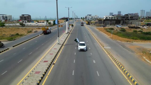 Karachi, Pakistan - 2 August 2025:
A white car driving on a public road with a Pakistani national flag displayed on the door.