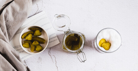 Picklatte with foam in a glass and pickles in a bowl on the table top view web banner