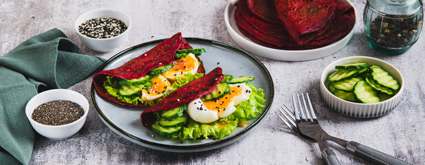 Beet chia tacos with egg, cucumber and lettuce on a plate on the table web banner