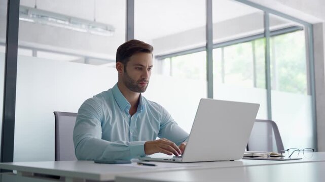 European businessman ceo specialist using computer technology app for work online. Young professional specialist latin hispanic businessman working on laptop pc sitting at desk in modern office space