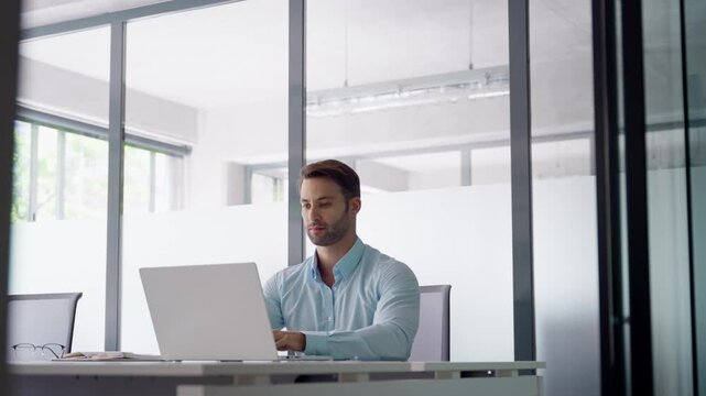 European businessman ceo specialist using computer technology app for work online. Young professional specialist latin hispanic businessman working on laptop pc sitting at desk in modern office space