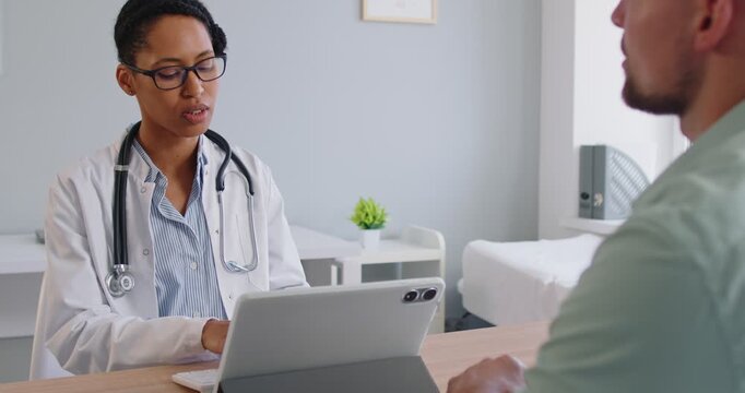 Doctor explains diagnosis to patient during clinic consultation during exam. Physician outlines medical plan and discusses symptoms and treatment with health care guidance. Medicine concept.