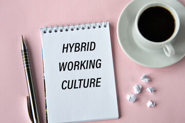 HYBRID WORKING CULTURE - words in a notebook on a pink background with a cup of coffee
