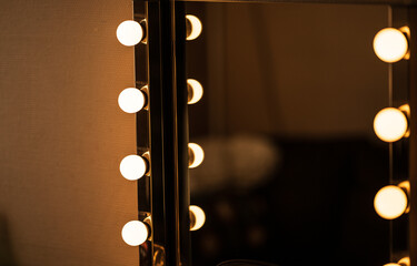 Illuminated dressing mirror in dark backstage room.