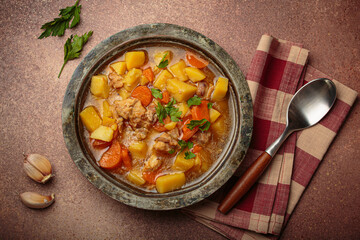 Hot chicken stew or soup with tender chicken pieces, chunky potatoes, and vibrant carrots garnished with fresh parsley in rustic bowl, comfort food for autumn and winter
