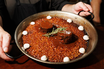 Chef serving paella with beef and rosemary