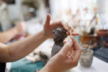 Sculptor hands modeling clay figure in studio