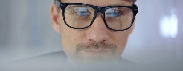 Businessman with glasses looking intently obscured partially by a translucent surface of laptop. Business people concept