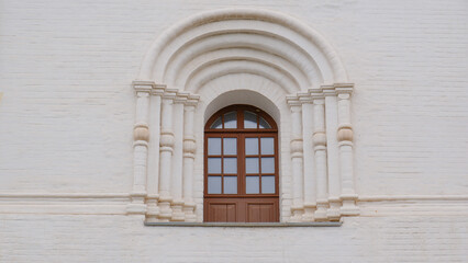Carved window against a white wall. The territory of the Astrakhan Kremlin, the architecture of the Assumption Cathedral.