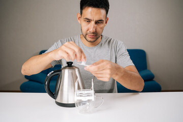 Portrait of focused coffee lover carefully placing drip coffee bag over glass cup, grinding fresh beans with pour-over kettle nearby, preparing artisan brewing method. Process of brewing coffee.