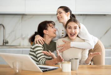 Women are reading email on laptop screen, cheering over good news, shouting triumphantly