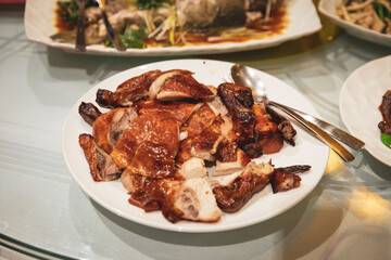 Close-up of sliced Cantonese roast duck served on white plate, golden brown crispy skin and juicy meat arranged neatly with serving utensils