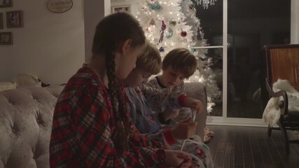 Happy children watching a video on a digital tablet together in a cozy, Christmas decorated living room at home