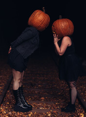 Spooky autumn evening with friends wearing pumpkin heads in a quiet forest setting