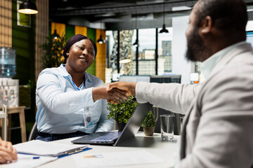 Black applicant and HR expert sharing a handshake as a warm welcome after being accepted within the corporate organization, preparing for employment paperwork and onboarding. Business people.