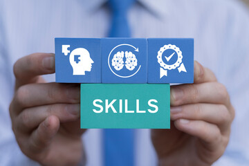 Concept of soft skills, thinking skill, new skill, reskill for evolution. Business person holding blocks with icons sees the word SKILLS. Coach focused on motivation to skills improvement.