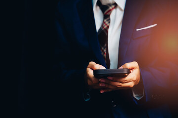 Business Professional in Suit Using Mobile Phone with Dark Background, Focus on Technology and Communication Essentials