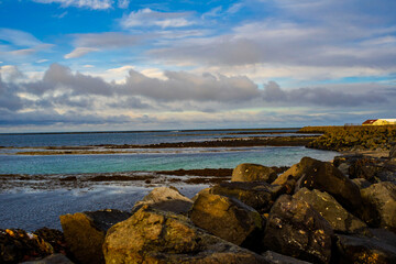 Rocky coastal landscape with calm sea and cloudy blue sky