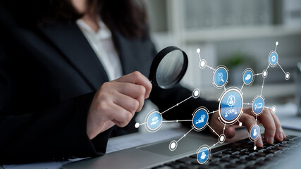 A business professional uses a magnifying glass to examine data analytics and customer relations, showcasing a modern office environment focused on technology and insight. Tessel